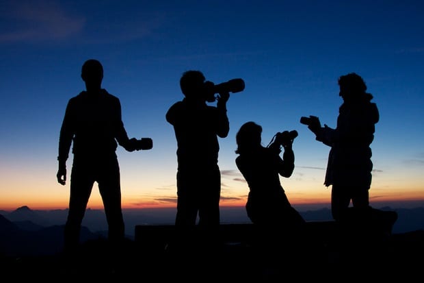 Four photographers silhouetted against a sunset