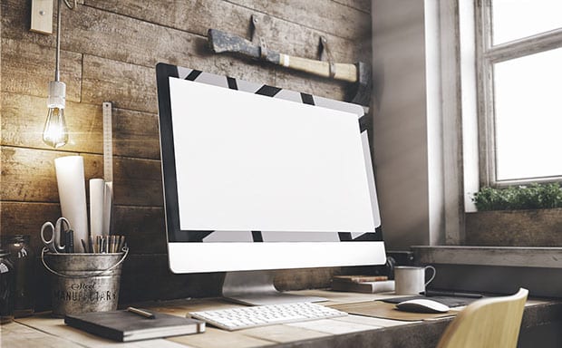 Computer on a desk with various writing tools