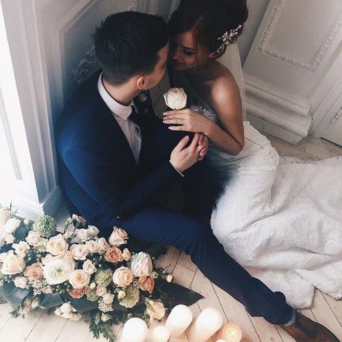 Newlyweds sit on the floor and gaze into each other's eyes.