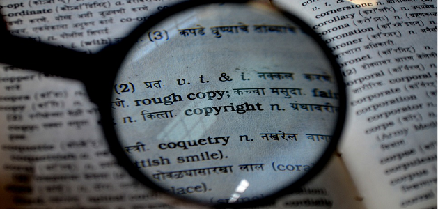 The word Copyright in a dictionary, seen through a magnifying glass