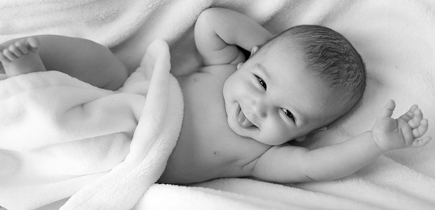 A black and white photo of a baby laying on a blanket