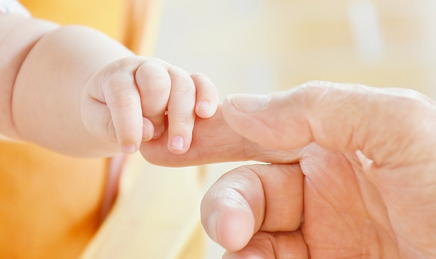 A baby grabbing a person's finger
