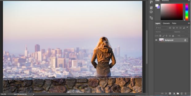 An image of a woman sitting on a stone wall overlooking a city, with the foreground carefully selected