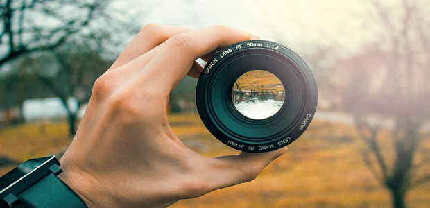 Someone holding a camera lens up to a fall scenery