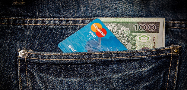 A credit card and paper money in a jeans pocket