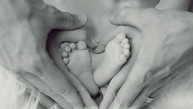 A mom and dad's hands making a heart about their baby's feet