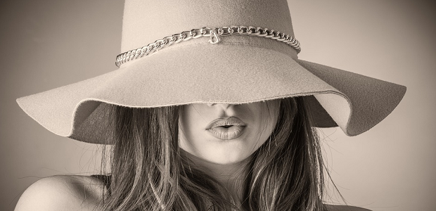 A grey-scale portrait of a woman in a hat, which covered half of her face