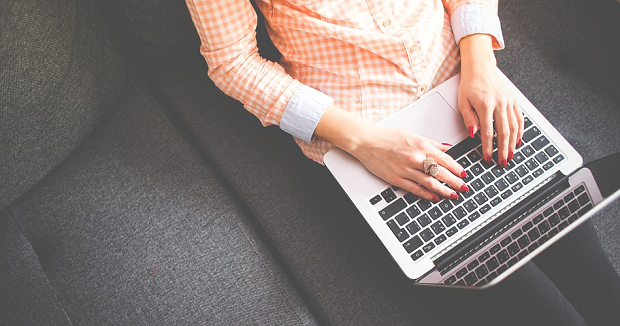 A woman working at a laptop on a black couch