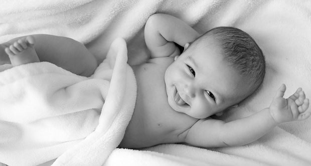 A black-and-white image of a baby laying in a blanket