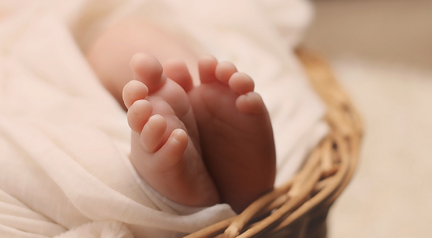 A baby laying in a basket, zoomed in on their feet