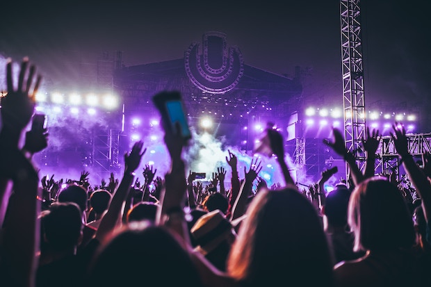 Crowd of people and purple-lit outdoor stage