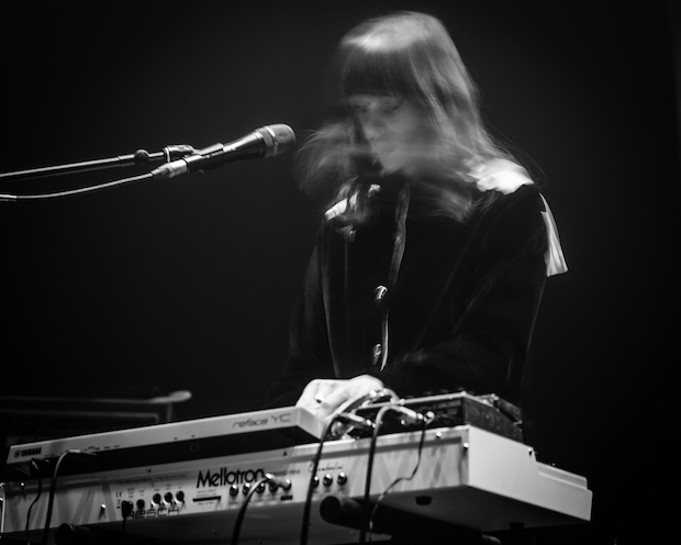 Keyboardist whose face is blurred in motion. Her keyboard and microphone are crisp in the shot.