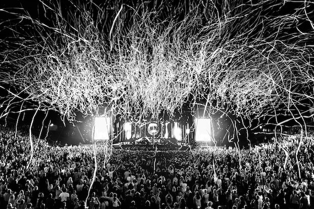 Outdoor stage with large crowd and streamers falling from the sky