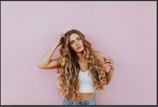 Portrait of blonde woman against pale pink background