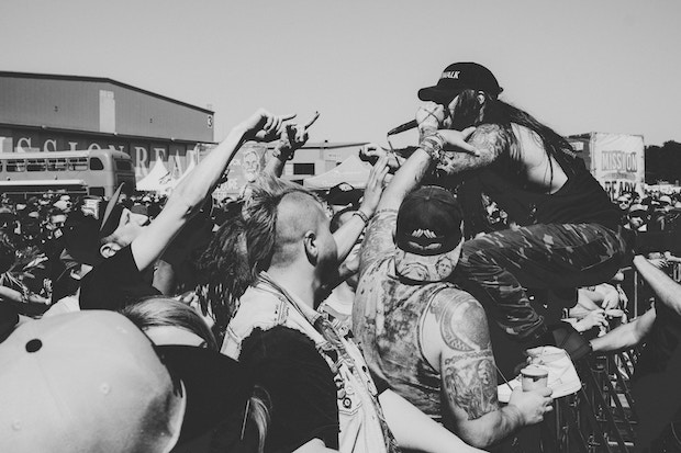 Musician singing into microphone while standing over crowd