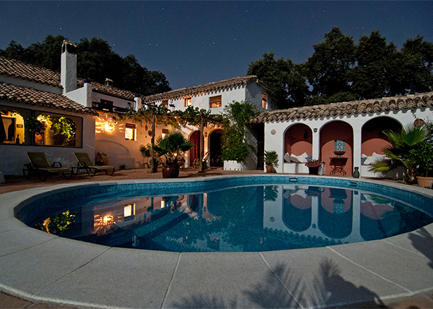 Backyard shot of home with lighted porch and in-ground pool