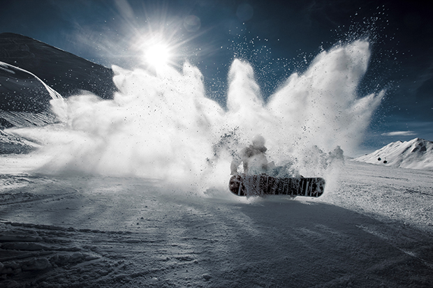 Snowboarder spraying snow on a trick