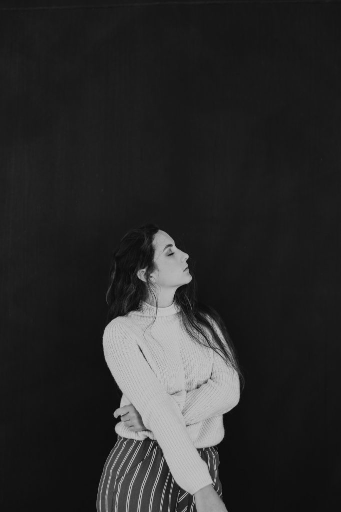 A black and white portrait of a girl posing in front of a black background