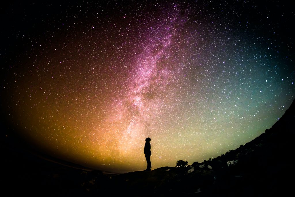 A silhouette of a man looking upwards towards the starry sky 