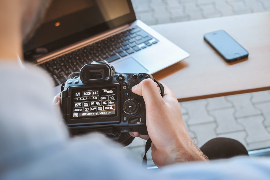 Over the shoulder shot of a person holding a camera and changing its setting