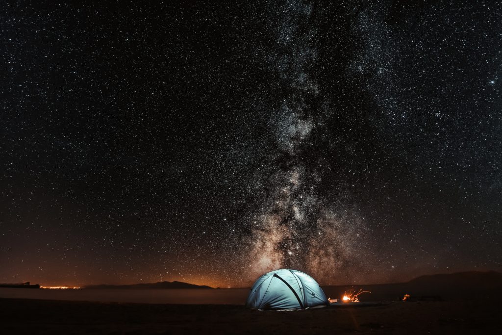 A blue colored tent with the background of the night sky with the Milky Way 