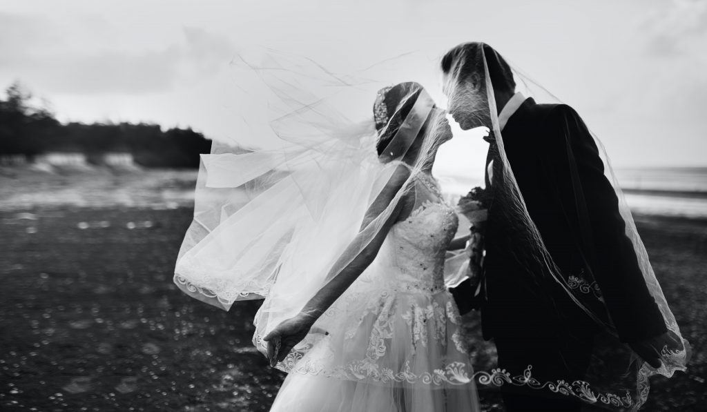 A bride and groom leaning in for a kiss under the bridal veil