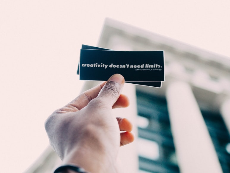 A person holding a black paper slip with a quote written on it