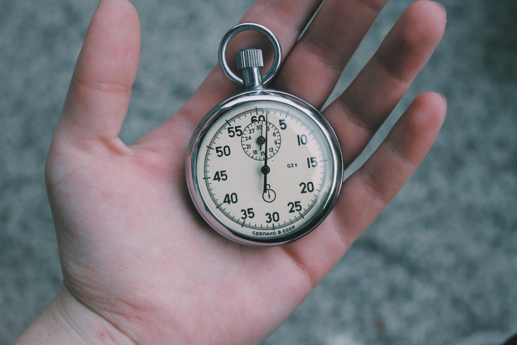 A close up of a person's hand holding a stopwatch